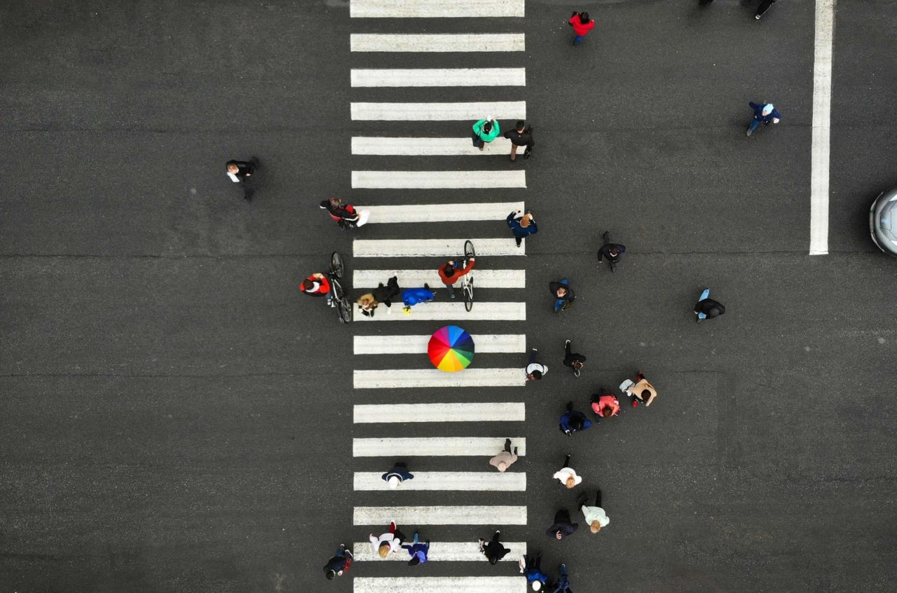 aerial people crowd pedestrian crosswalk zebra crossing top view one person from crowd holds colorful umbrella scaled e1643912091407